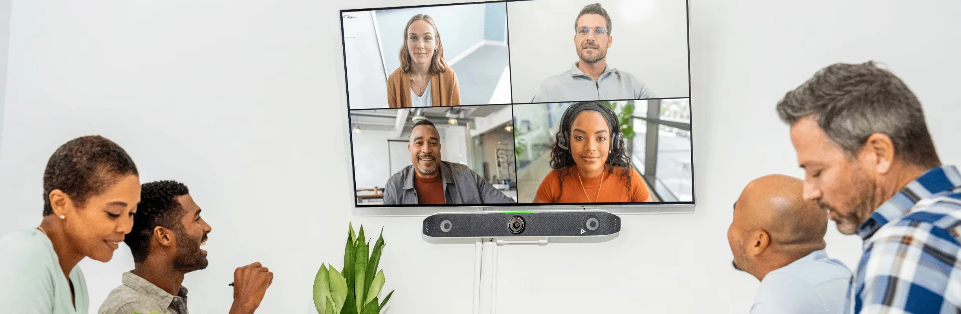 Huddle room com quatro pessoas em reunião por vídeo